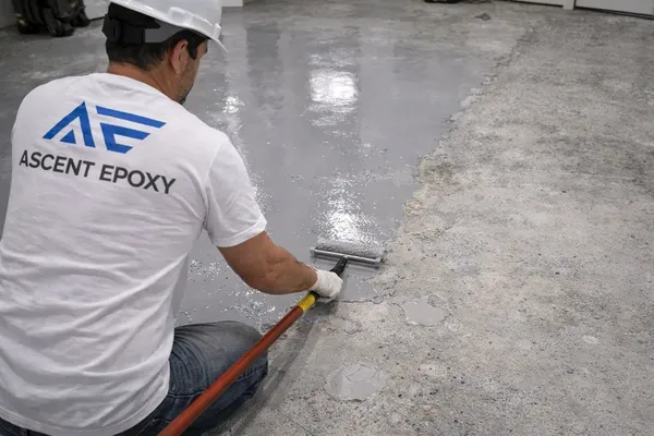 Installer rolling a gray coating over prepared concrete, by the Ascent Epoxy team